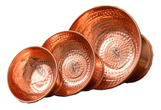 Three handcrafted hammered copper singing bowls in different sizes displayed on a wooden table for meditation, sound healing, mindfulness and spiritual practice.