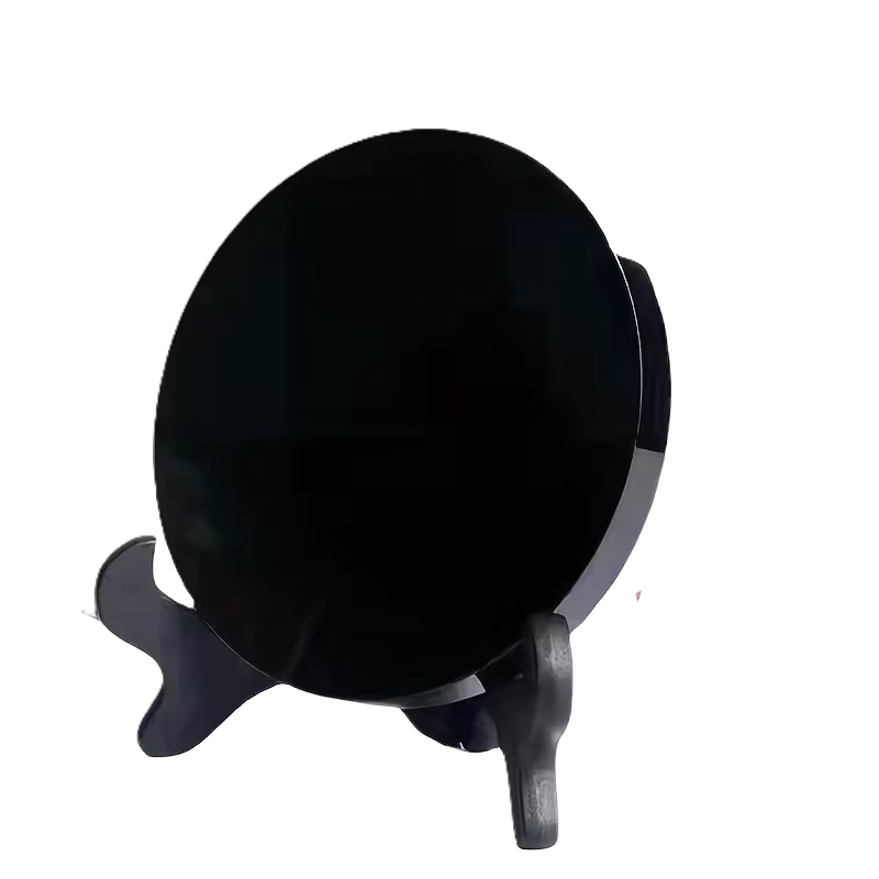 A polished black obsidian scrying mirror displayed on a decorative stand against a white background, traditionally used for mirror scrying and spiritual divination.